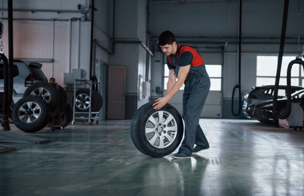 one last wheel mechanic holding a tire at the repair garage replacement of winter and summer tires